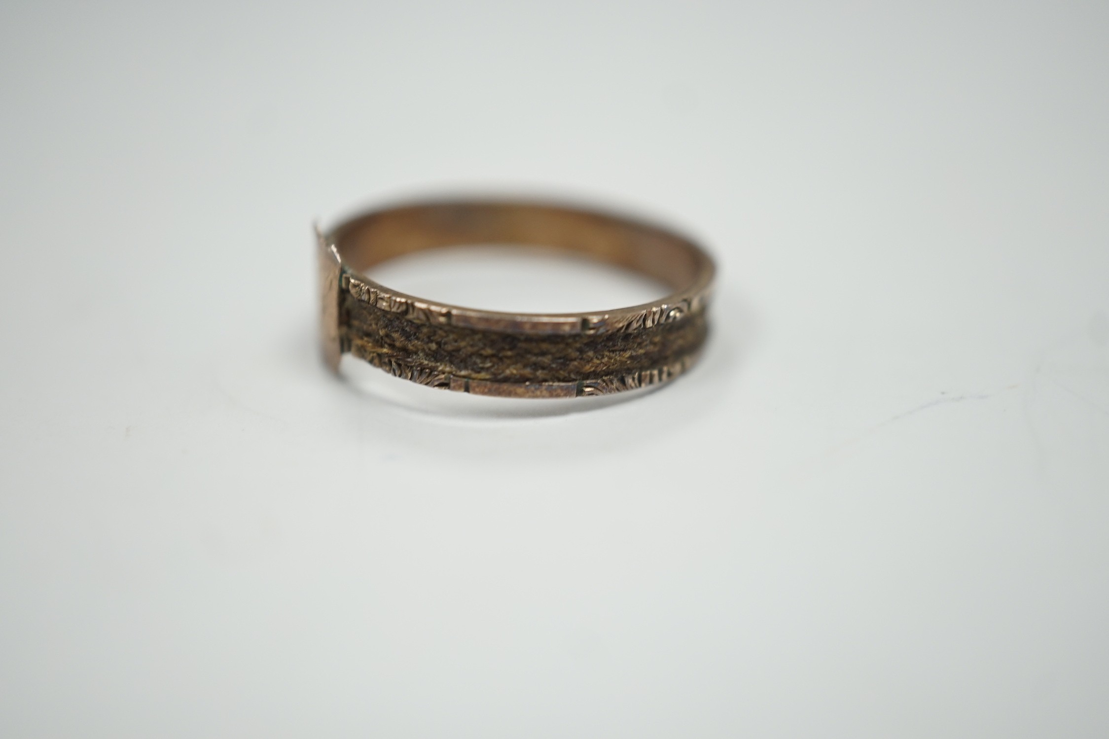 A Victorian yellow metal mourning ring, with engraved monogram and shank inset with plaited hair, size O, gross weight 1.2 grams.